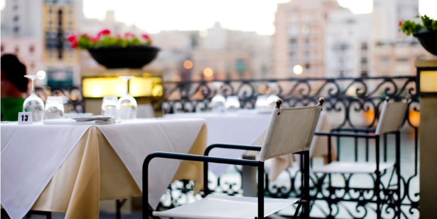 Een lege tafel en stoel, gedekt met glazen en borden, een restaurantsetting op een terras in de zomer